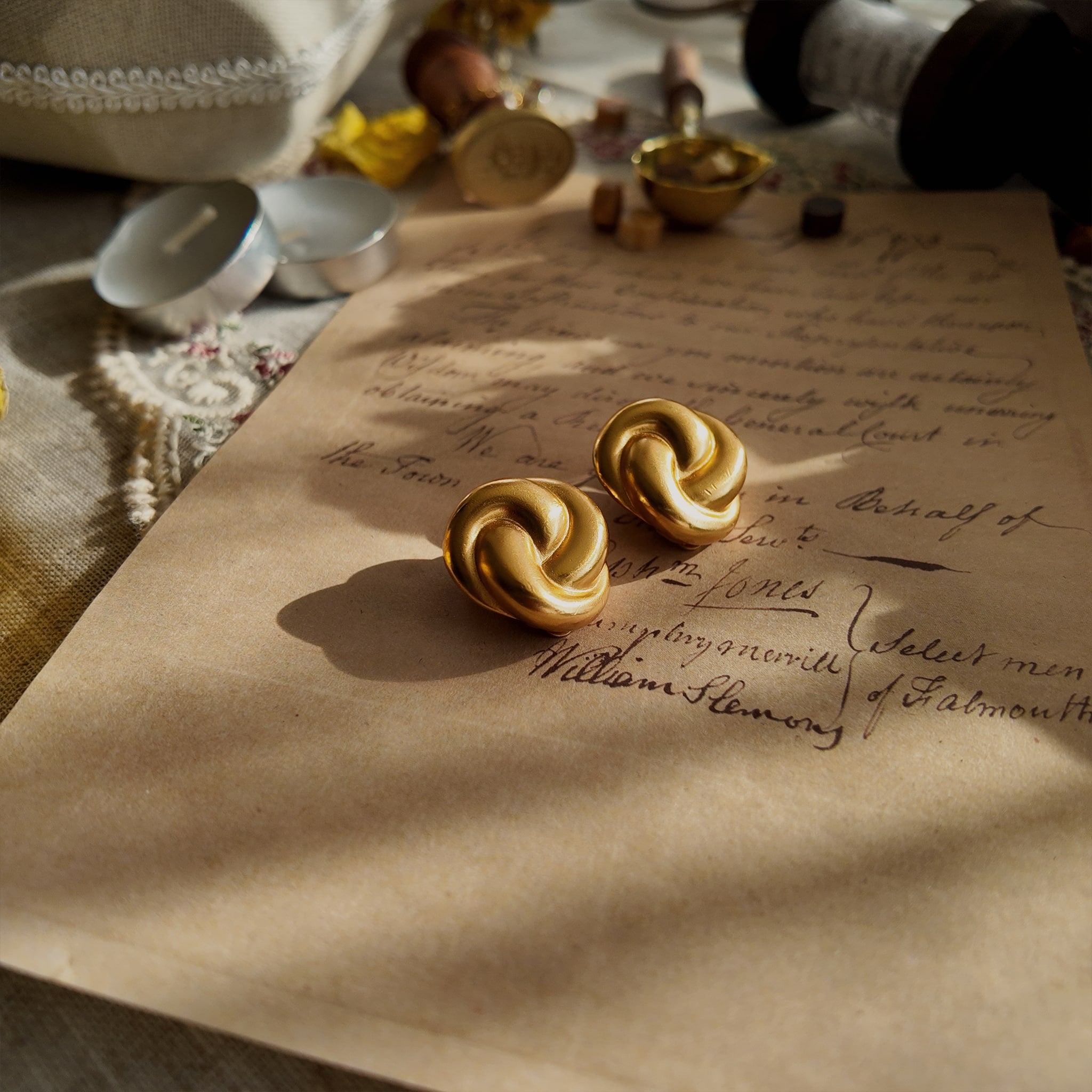 A detailed view of the matching Anne Klein knot earrings, echoing the bracelet's design with a bold, confident circle of warm, brushed matte gold.