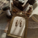The "Art of Subtle Brilliance" Monet earrings styled on a wedding invitation to emphasize their identity as the perfect, timeless accessory for a bride or wedding guest.