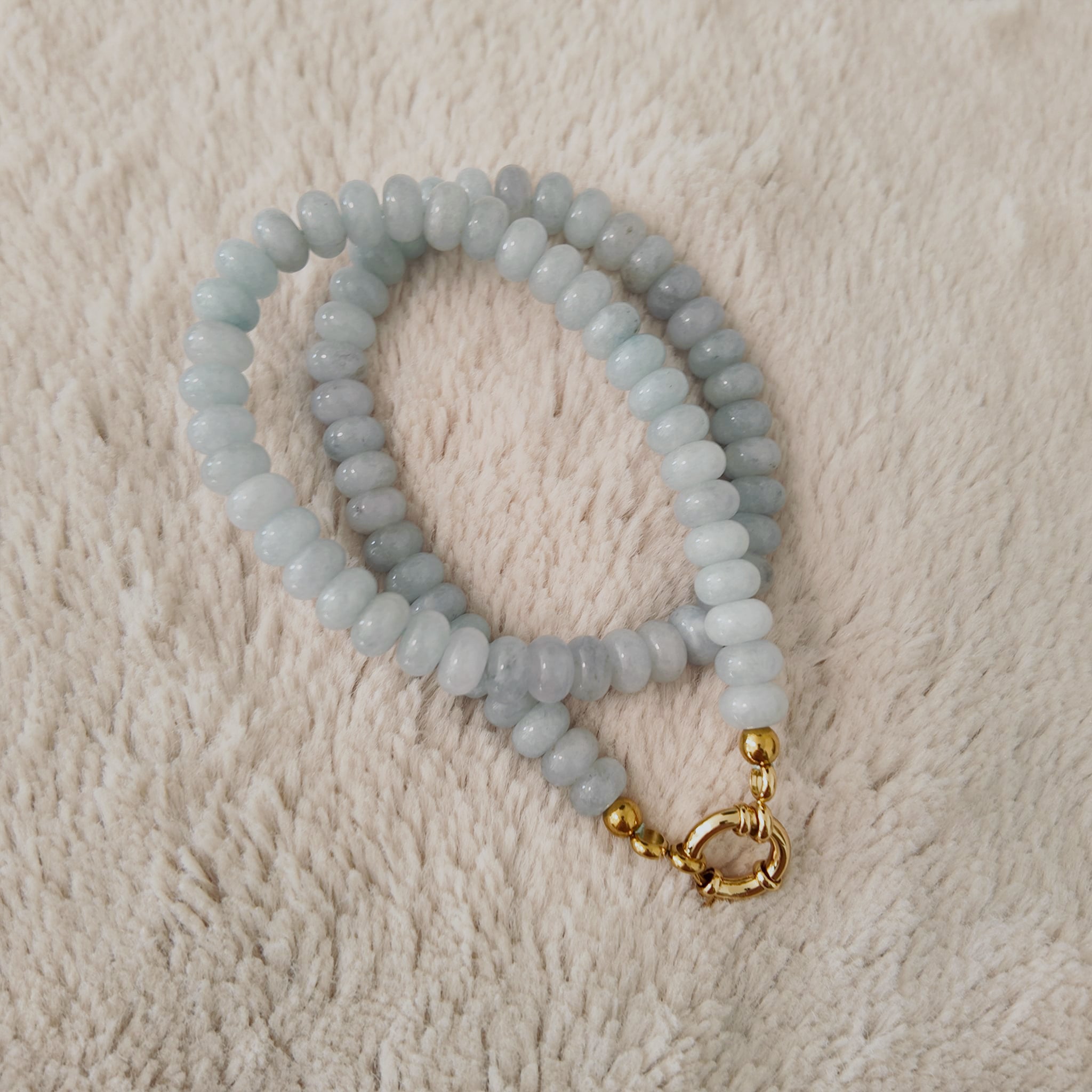 An angled view of the handmade necklace, highlighting the organic, flat-round (rondelle) cut of the stones and the natural, milky blue color.