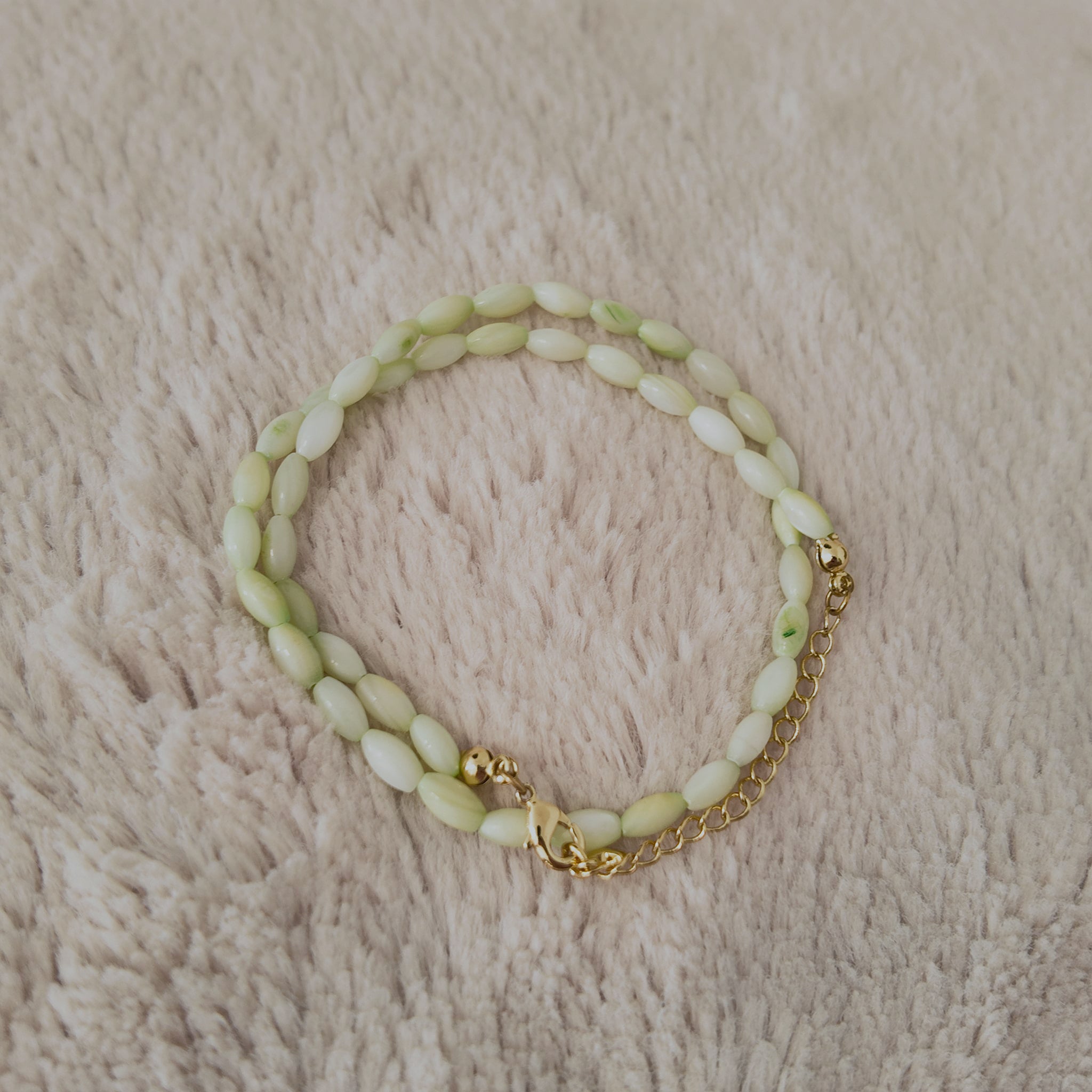 An angled view of the handmade necklace, highlighting the natural, pearlescent luster (orient) of the shell beads and the fluid drape of the choker.