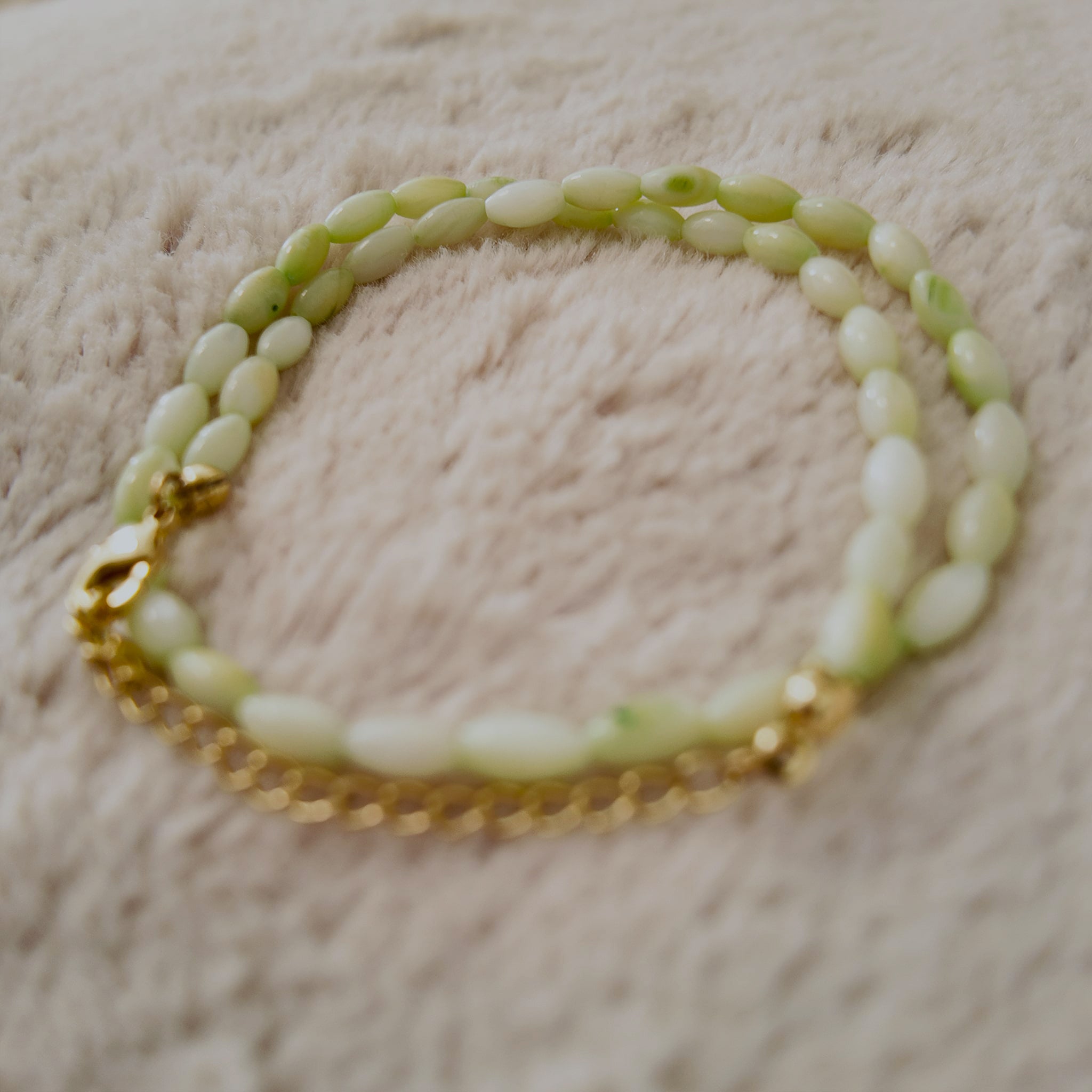 An angled view of the handmade necklace, highlighting the natural, pearlescent luster (orient) of the shell beads and the fluid drape of the choker.