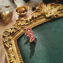 An angled view of the red enamel flower earrings, highlighting the immaculate, pearlescent finish of the enamel and the bright, sparkling central rhinestone.
