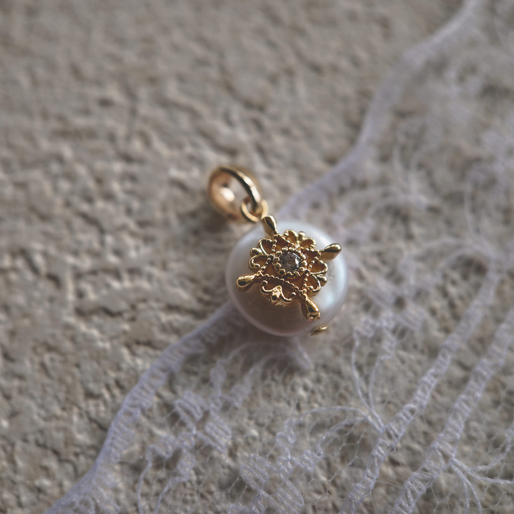 A macro shot detailing the soft, natural luster of the freshwater pearl and the tiny, star-like sparkle of the central cubic zirconia in the filigree.