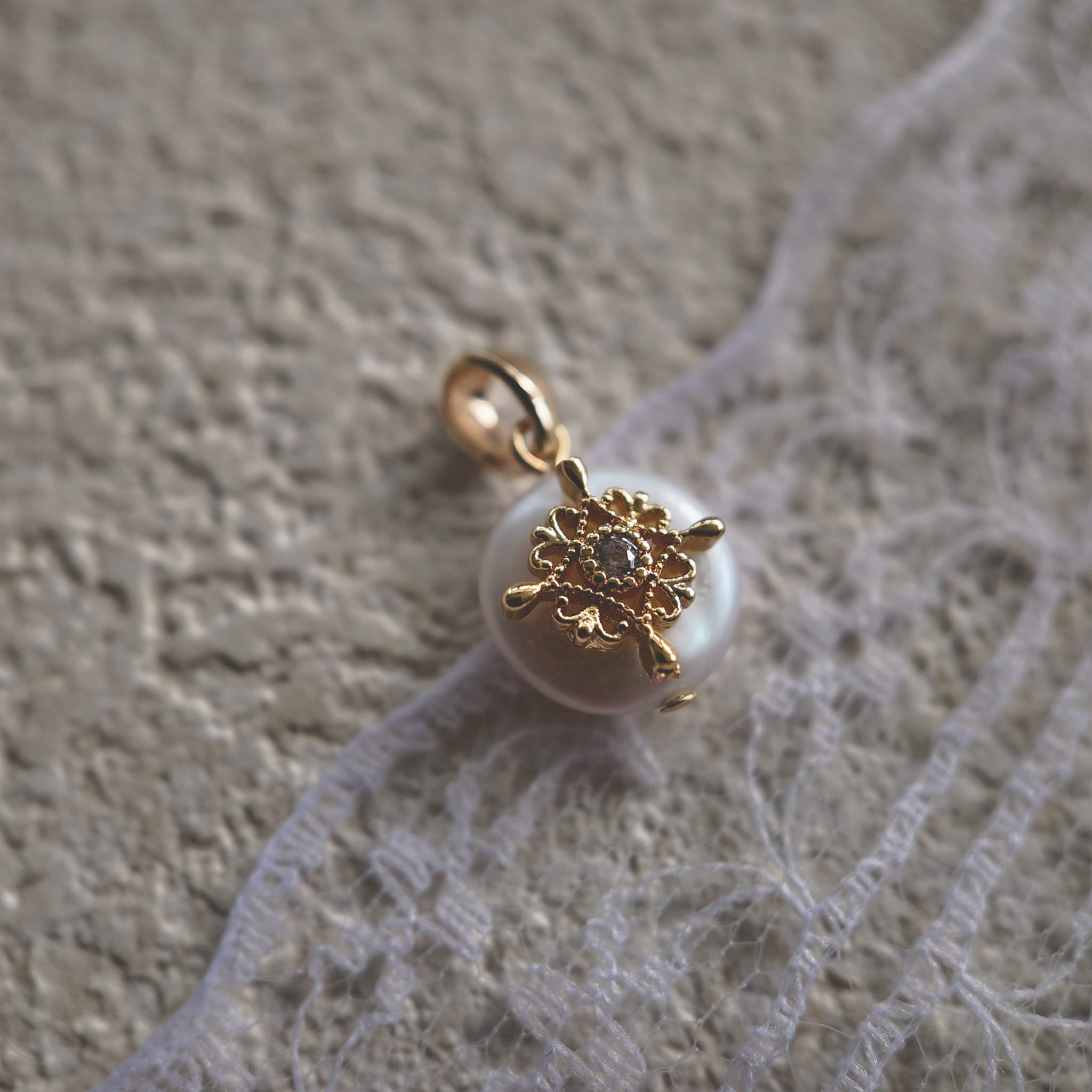 A macro shot detailing the soft, natural luster of the freshwater pearl and the tiny, star-like sparkle of the central cubic zirconia in the filigree.