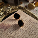 A macro shot detailing the sharp, high-contrast border between the deep black resin and the bright, polished gold-tone metal on these minimalist earrings.