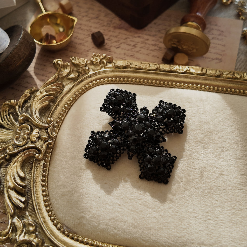 A macro shot detailing the intricate, lace-like filigree and the light-absorbing quality of the black glass rhinestones on this piece of Vampire jewelry.