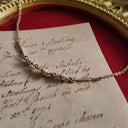 An angled view of the caged pearl necklace, highlighting the raw, sculptural quality of the entangled metal and the soft luster of the pearls within.