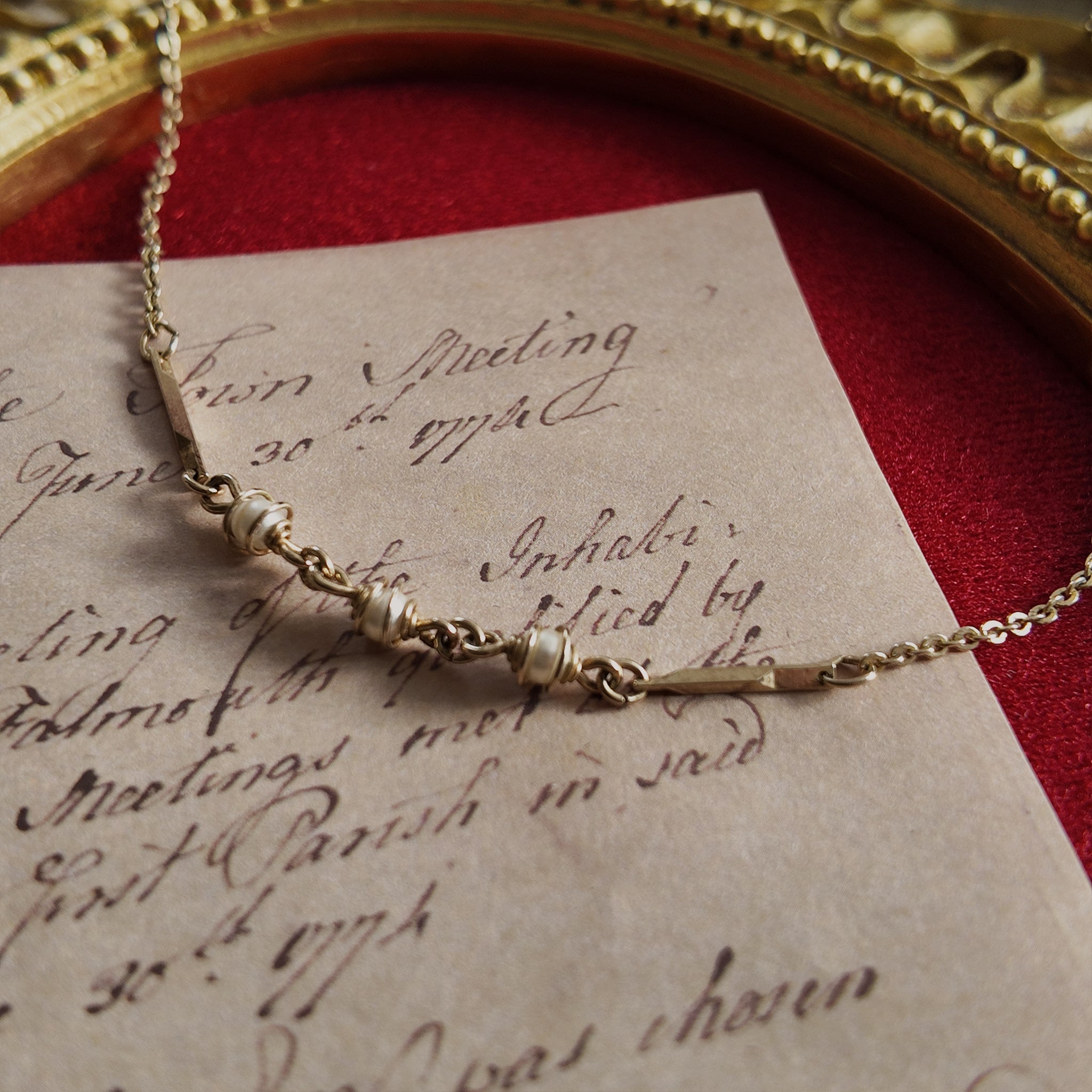 An angled view of the caged pearl necklace, highlighting the raw, sculptural quality of the entangled metal and the soft luster of the pearls within.