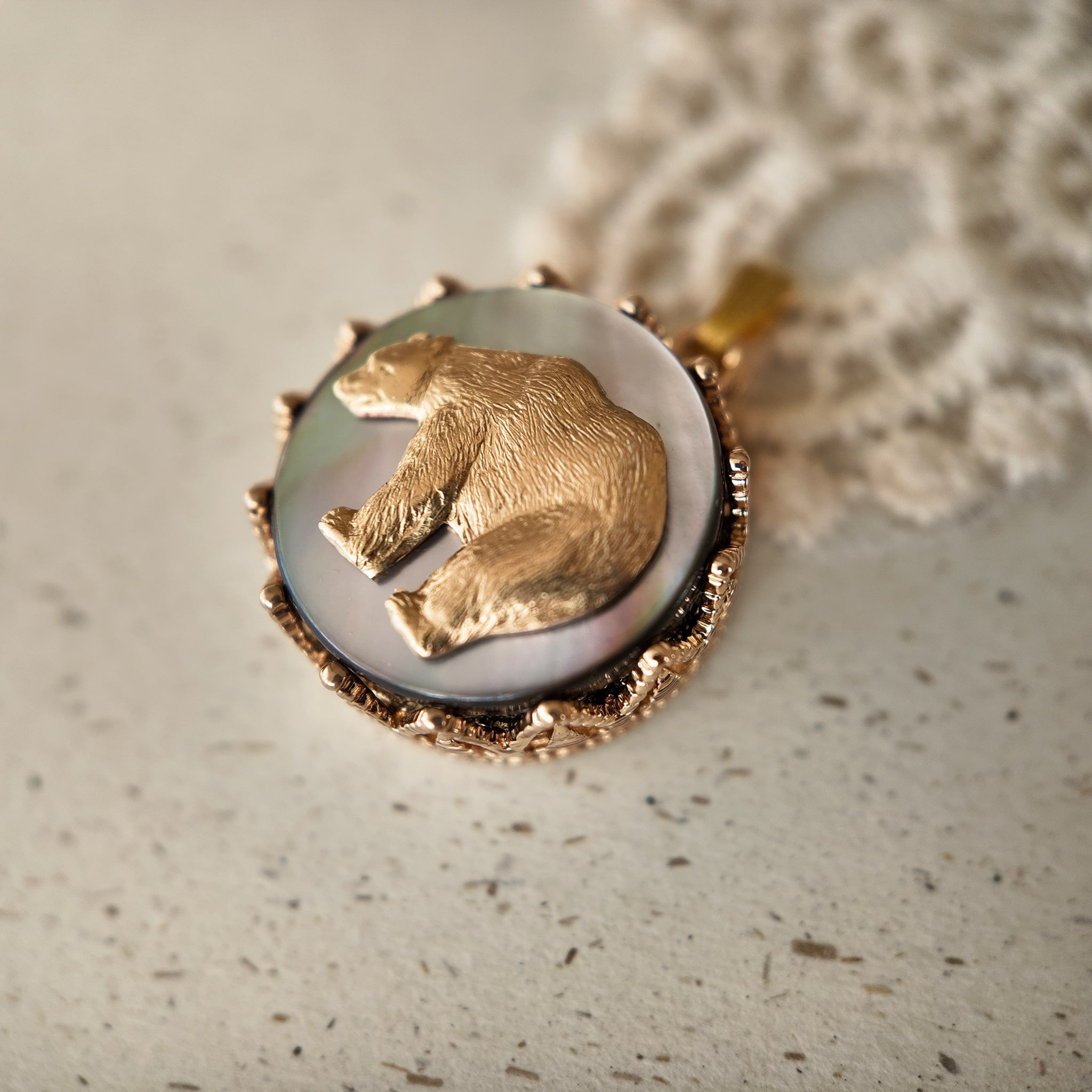 The "Bear Who Dreamed of Stars" celestial necklace from The Character Arc, featuring a vintage brass bear pendant on an iridescent Black Mother-of-Pearl base.
