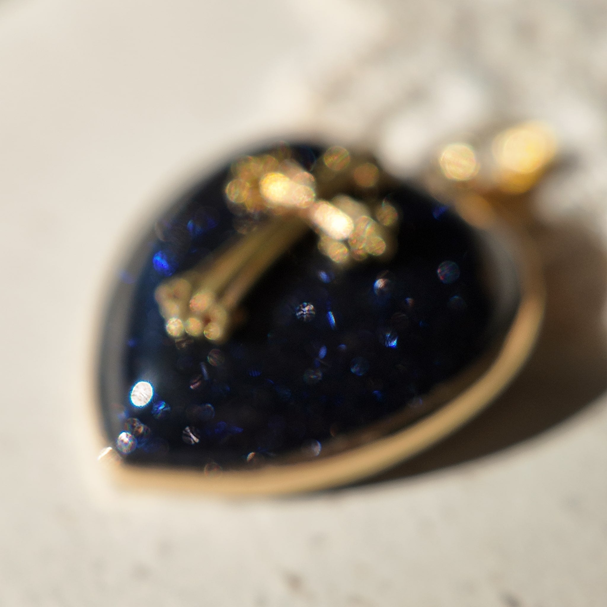 A macro shot capturing the thousands of tiny, star-like sparkles within the polished blue goldstone of the "Galactic Faith" necklace.