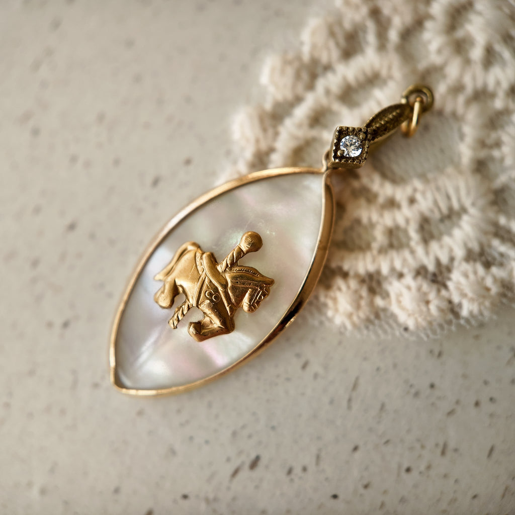 The "Ticket to Dreamland" coquette-style necklace, featuring a vintage brass carousel horse pendant on an iridescent Mother-of-Pearl marquise-shaped base.
