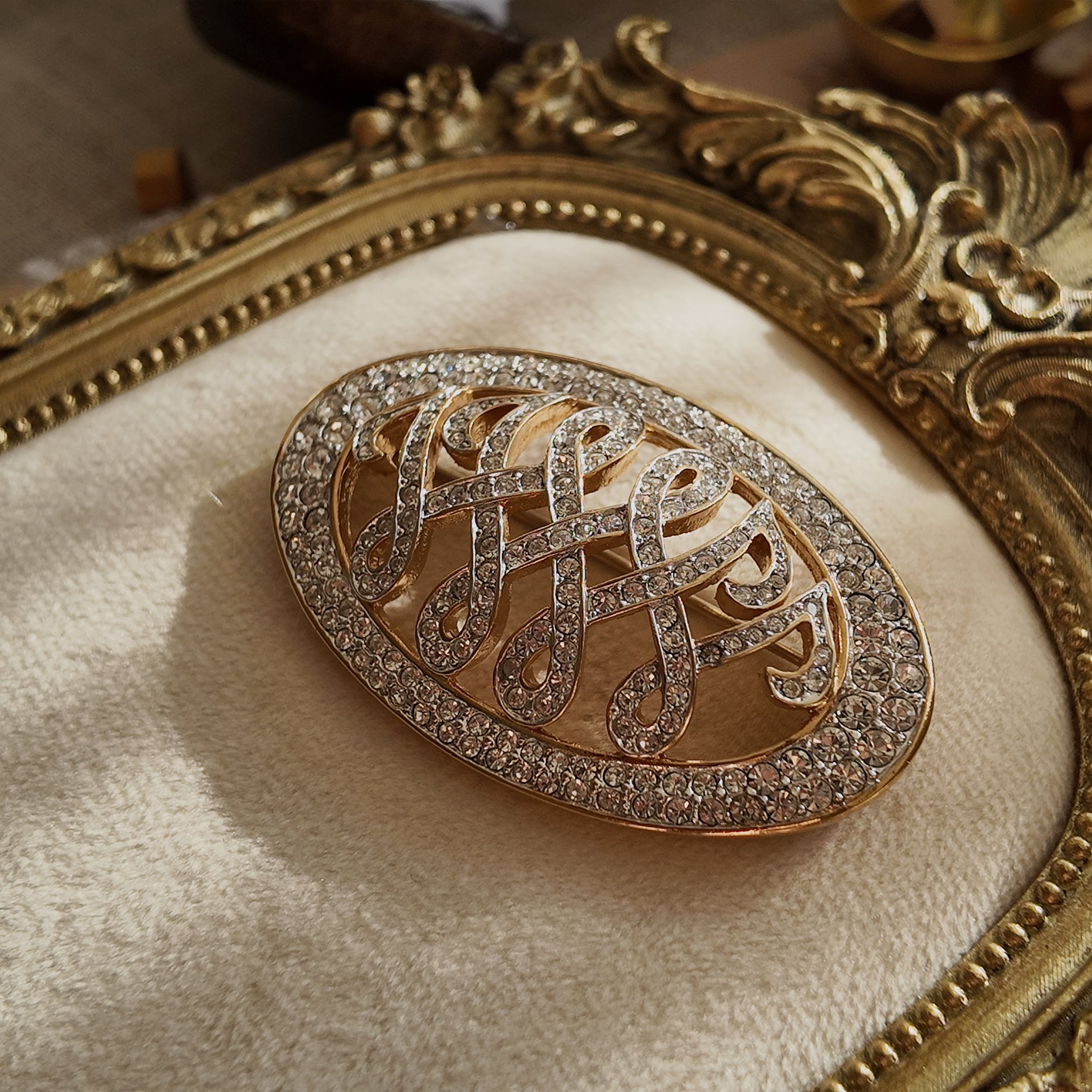 An angled view of the crystal "WW" brooch, highlighting the fiery, diamond-like sparkle of the hand-set pavé rhinestones in the gold-plated setting.