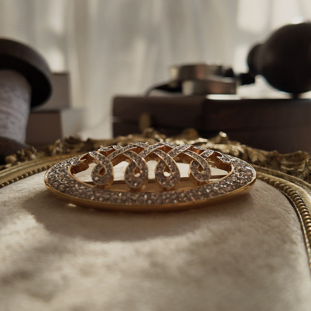 An angled view of the crystal "WW" brooch, highlighting the fiery, diamond-like sparkle of the hand-set pavé rhinestones in the gold-plated setting.