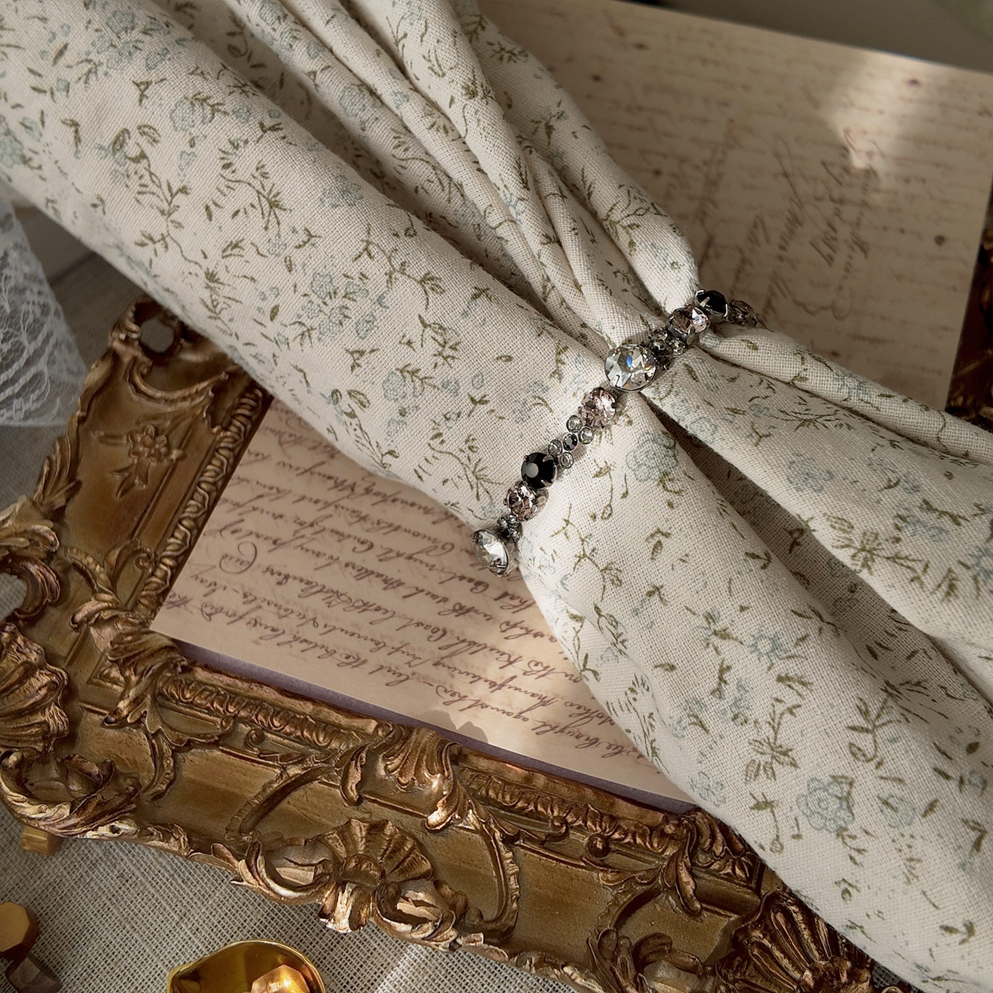 A dainty Sorrelli crystal bracelet worn on a wrist, showcasing its delicate size and its "sweet and sinister" pink and black color palette, perfect for Coquette style.