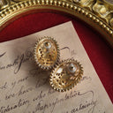 The reverse side of the earrings, showing the signature scrollwork texture that identifies them as authentic 1928 Jewelry, a mark of their vintage heritage.