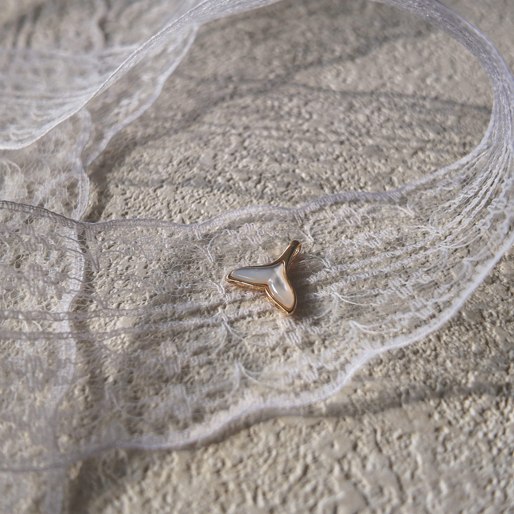 An angled view of the artisan charm, highlighting the beautiful, shifting luster of the Mother-of-Pearl that catches the light like a sunlit wave.