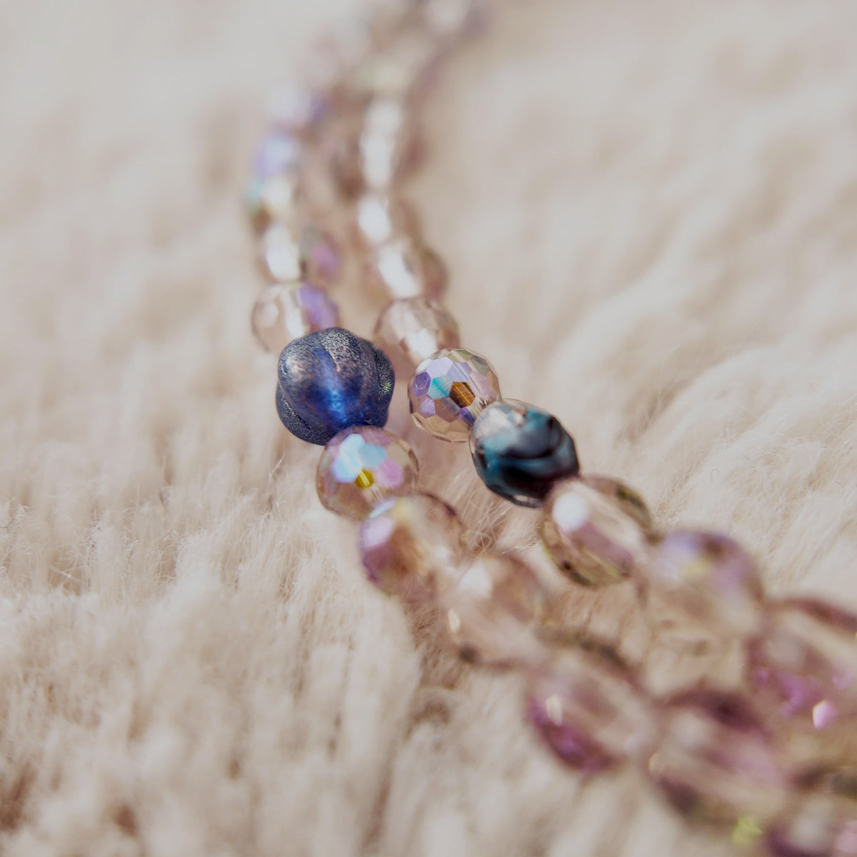 The "Dream Weaver," an artisan beaded necklace from The Character Arc, featuring faceted Czech glass beads in iridescent purple, amethyst, and pink agate stones.