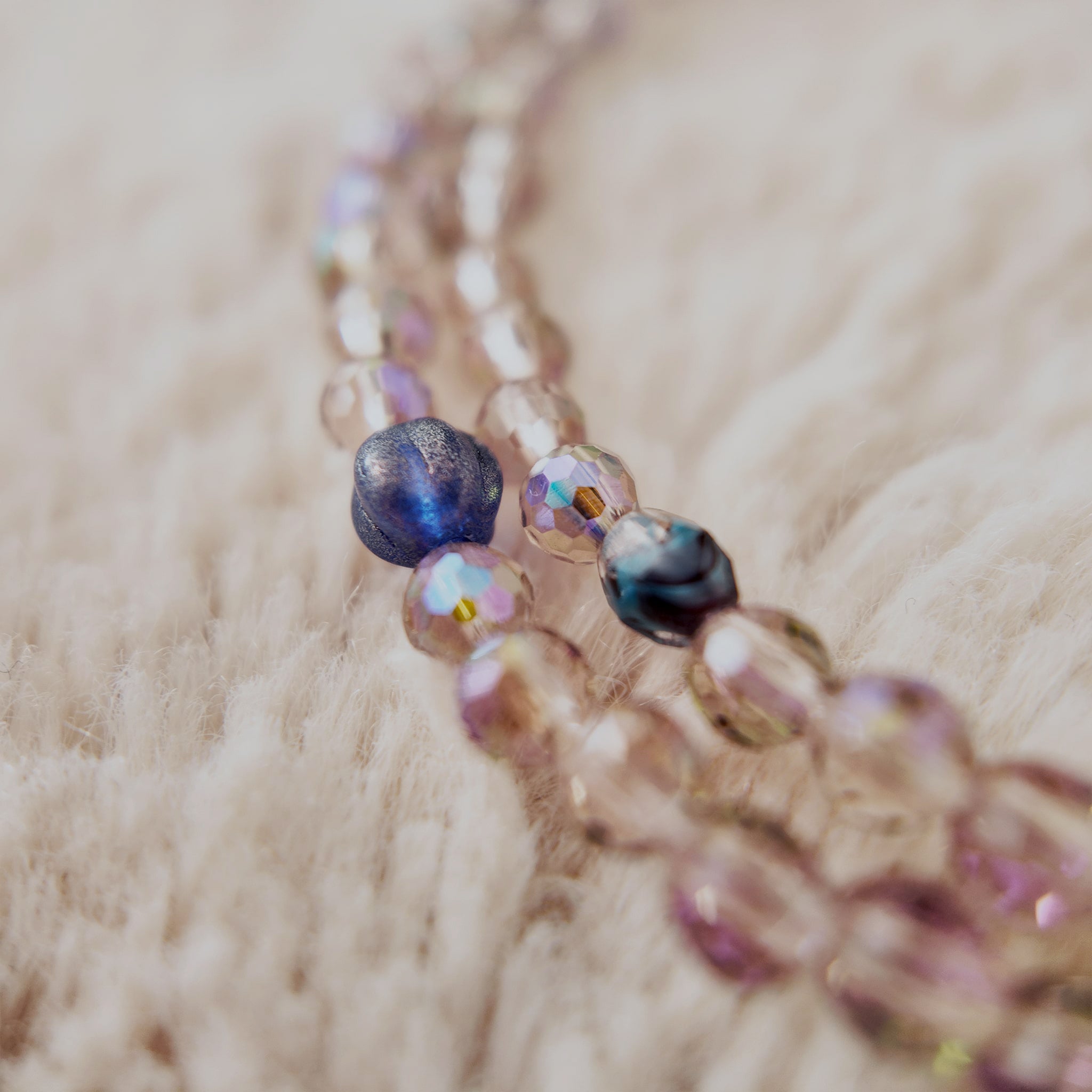 The "Dream Weaver," an artisan beaded necklace from The Character Arc, featuring faceted Czech glass beads in iridescent purple, amethyst, and pink agate stones.