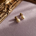 A macro shot honestly detailing the fine, hairline scratches on the gold-tone surface, a sign of this "well-loved" pair of vintage Avon earrings, sold as-is.