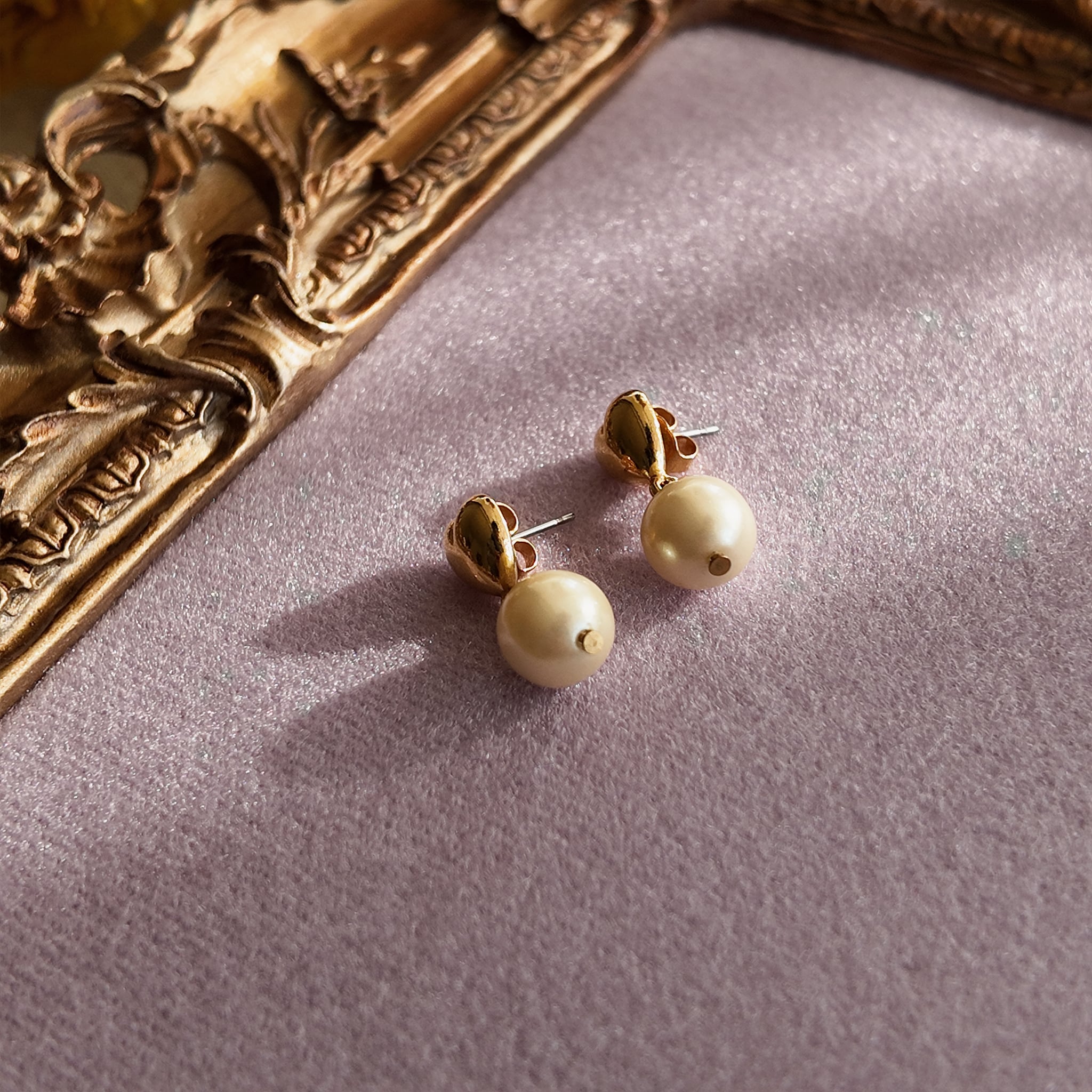 A macro shot honestly detailing the fine, hairline scratches on the gold-tone surface, a sign of this "well-loved" pair of vintage Avon earrings, sold as-is.