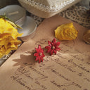 A macro shot detailing the tiny, golden stamen dots at the center of the flower, which add a touch of metallic warmth to the vibrant red petals.