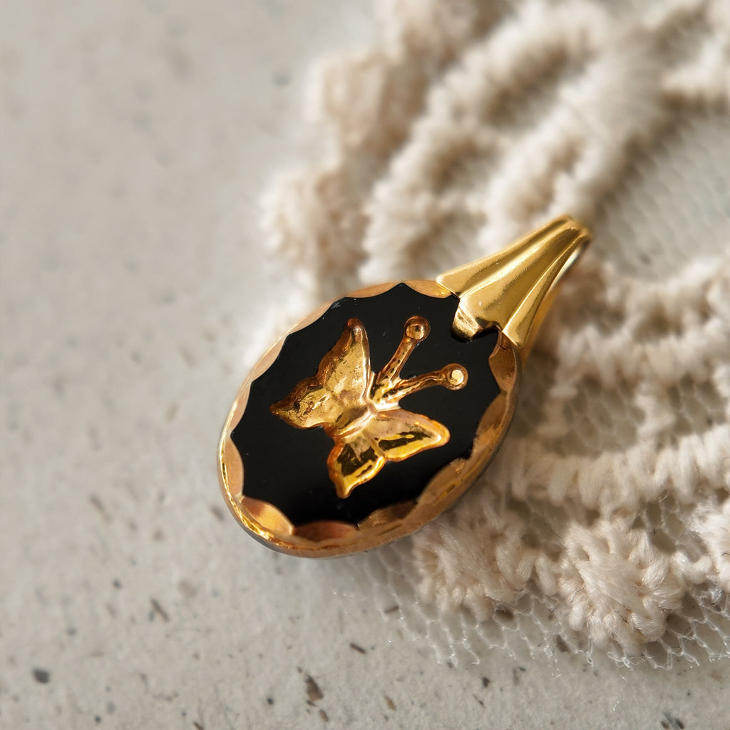 The "Shadow Butterfly" gothic necklace from The Character Arc, featuring a tiny, rectangular black West Germany glass intaglio pendant with a gold butterfly.