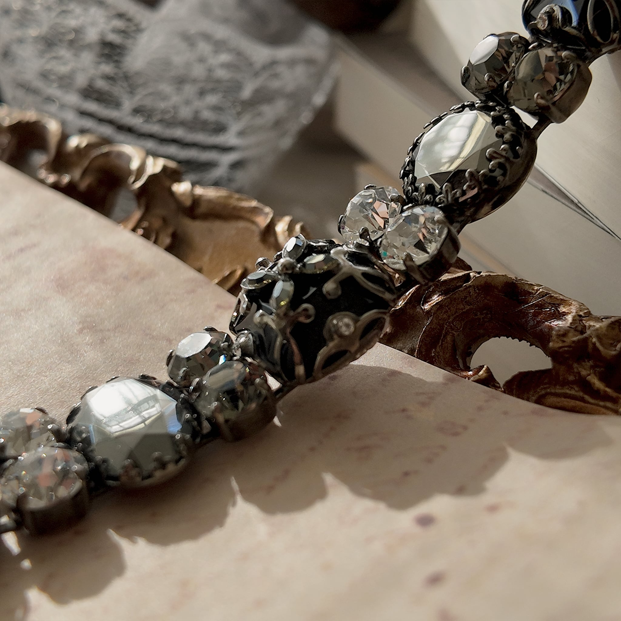 An angled view of "The Forbidden Scholar" Gothic bracelet, highlighting the intricate, lace-like metal filigree layered over the large, obsidian-like stones.