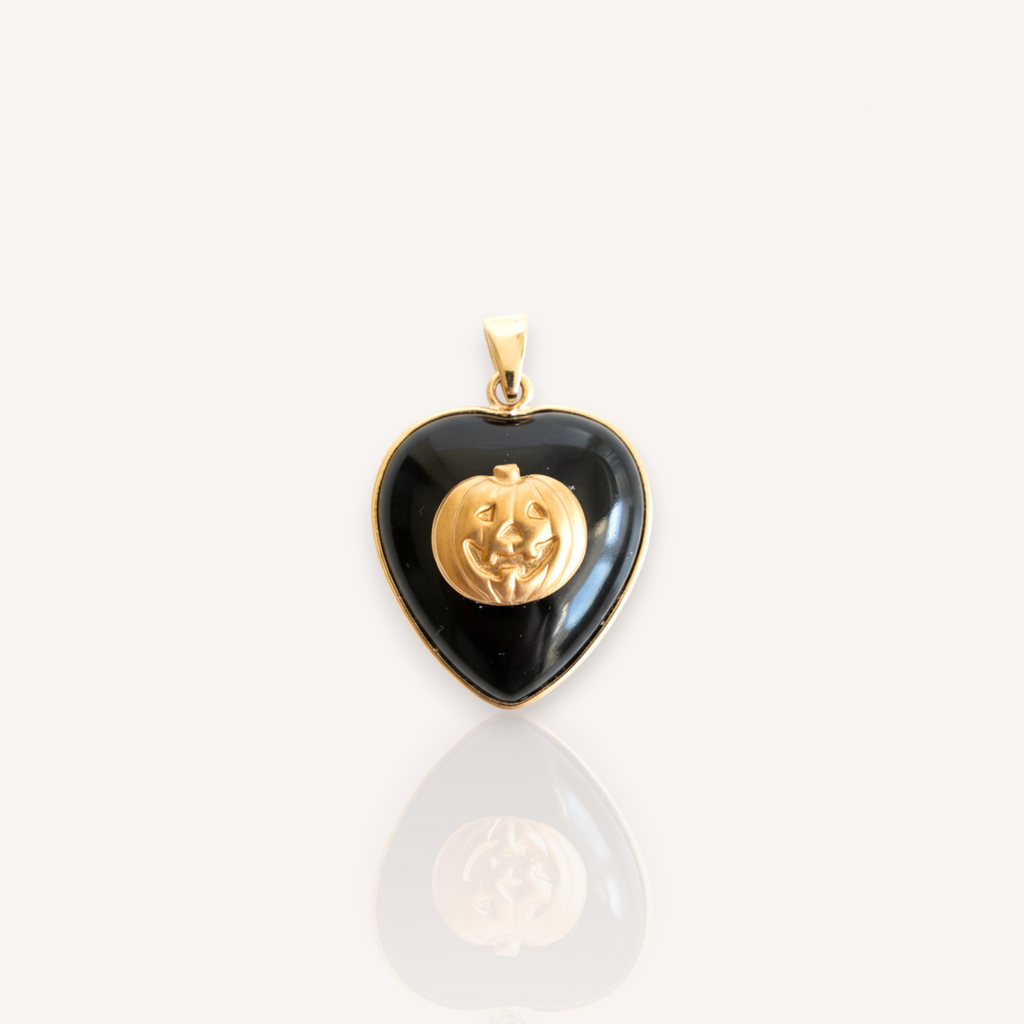 Front view of The Gothic Pumpkin pendant featuring a jet black onyx heart with a vintage brass Jack-o'-Lantern overlay.