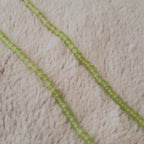 A macro shot detailing the magical "Cat's Eye" effect, a band of reflected light known as chatoyancy that moves across the surface of each green bead.