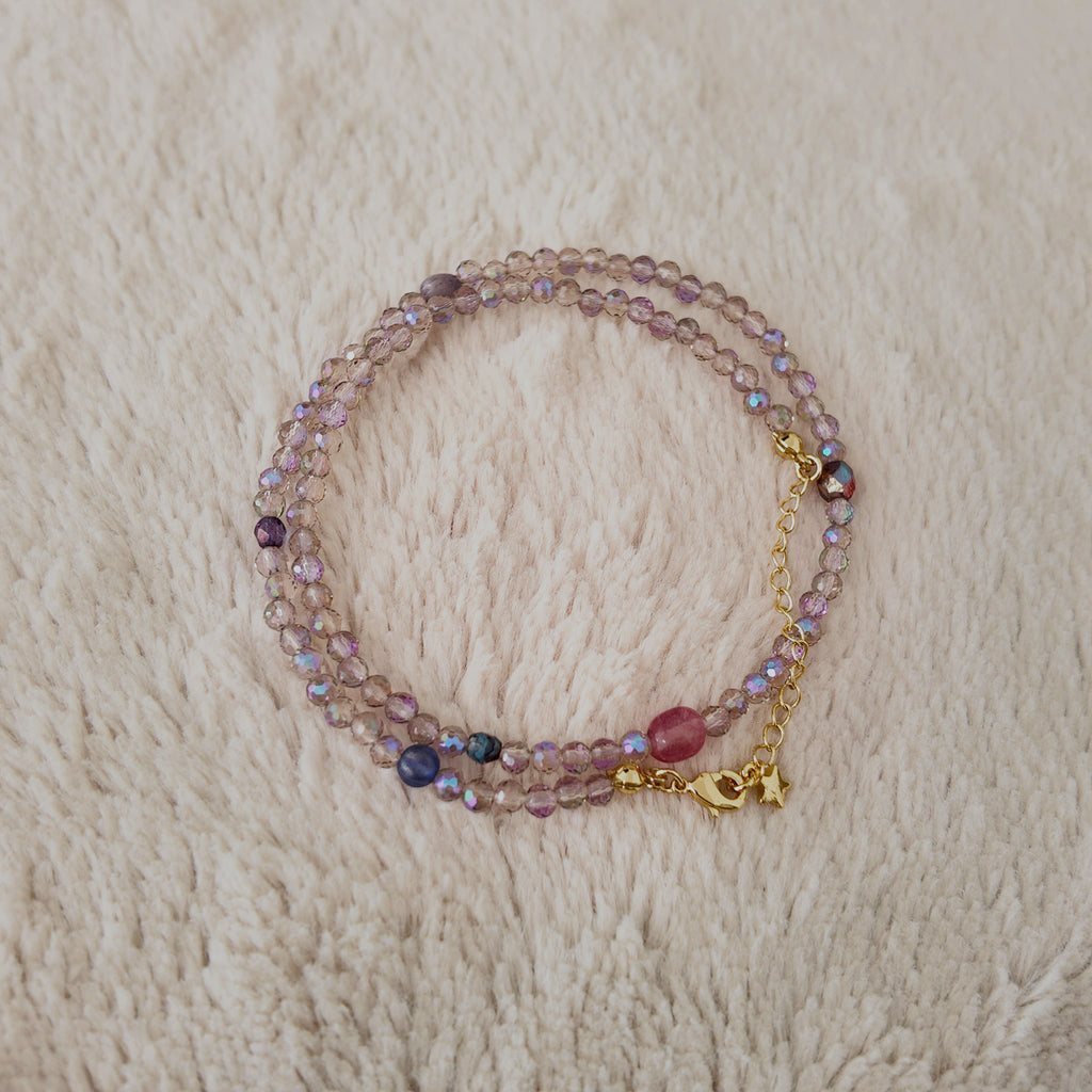 An angled view of the handmade necklace, highlighting the magical, shifting sheen of blue and gold on the iridescent, Aurora Borealis (AB) finished Czech glass.