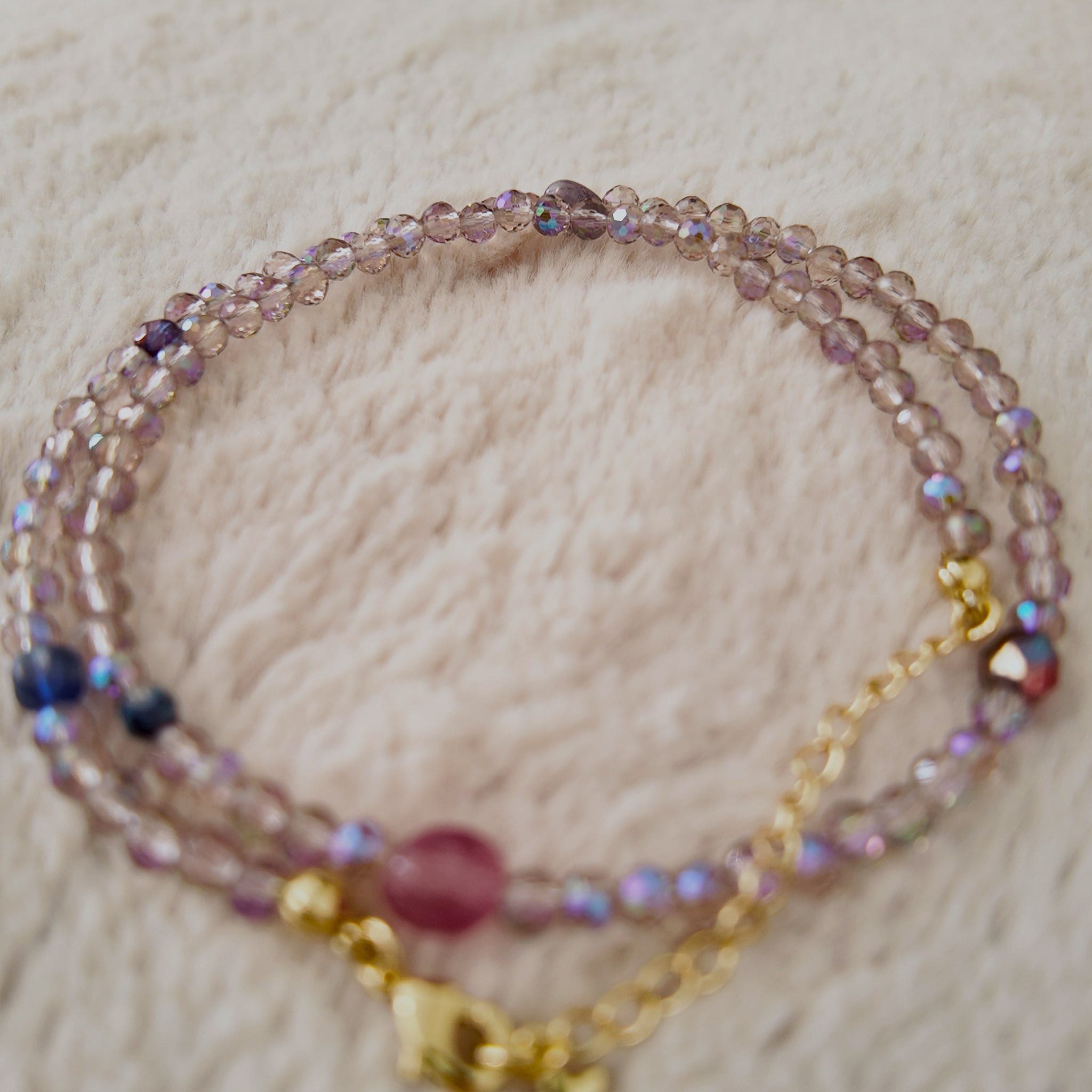 An angled view of the handmade necklace, highlighting the magical, shifting sheen of blue and gold on the iridescent, Aurora Borealis (AB) finished Czech glass.