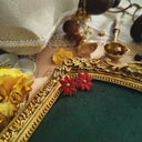 The "Island Girl" Avon earrings styled next to a tropical cocktail to emphasize their "carefree beach holiday" aesthetic and their role as the perfect summer accessory.