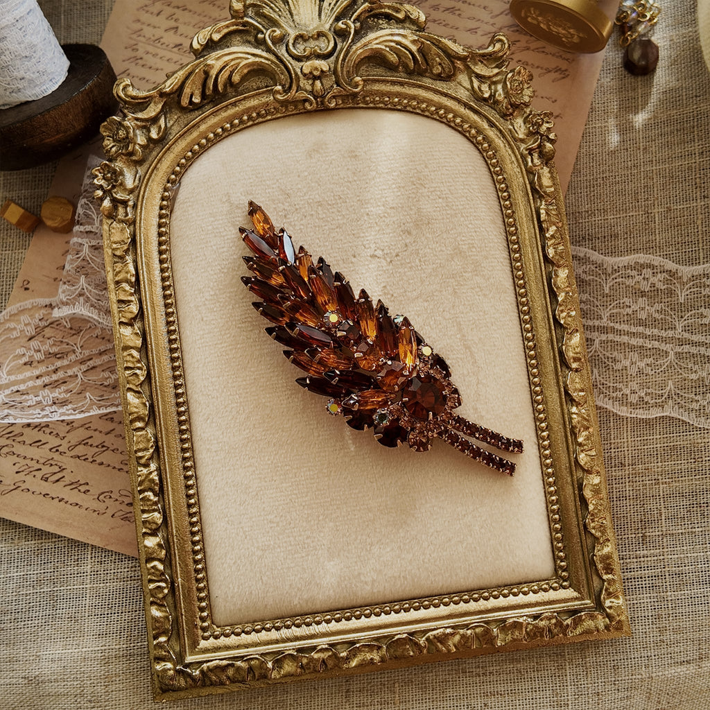 The Juliana "Secret Magician" brooch styled in a warm, sunset-like setting to emphasize its "riot of color" and its identity as a piece of wearable art.