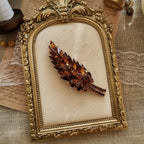 The Juliana "Secret Magician" brooch styled in a warm, sunset-like setting to emphasize its "riot of color" and its identity as a piece of wearable art.