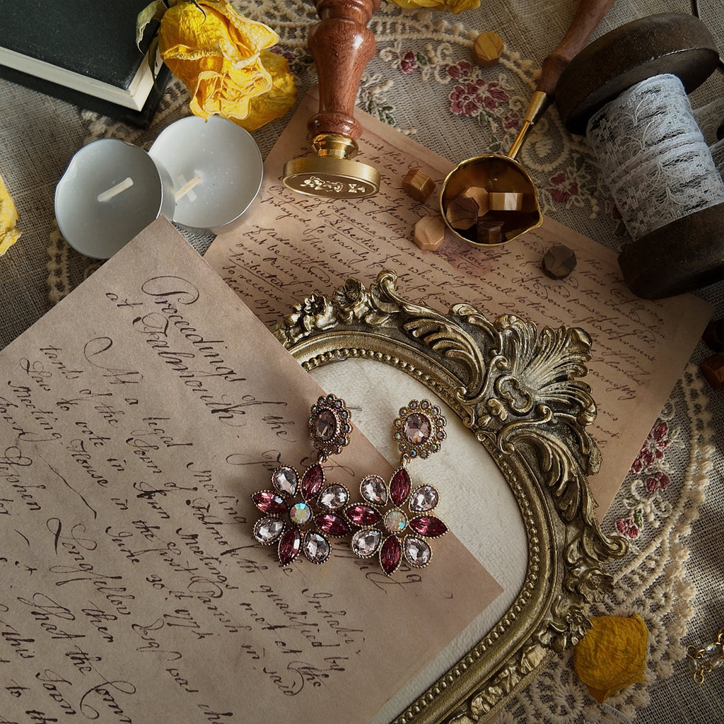 The "Garden is in Full Bloom" Monet earrings styled on pink silk to emphasize their "unapologetic beauty" and their identity as a piece of lavish, celebratory jewelry.
