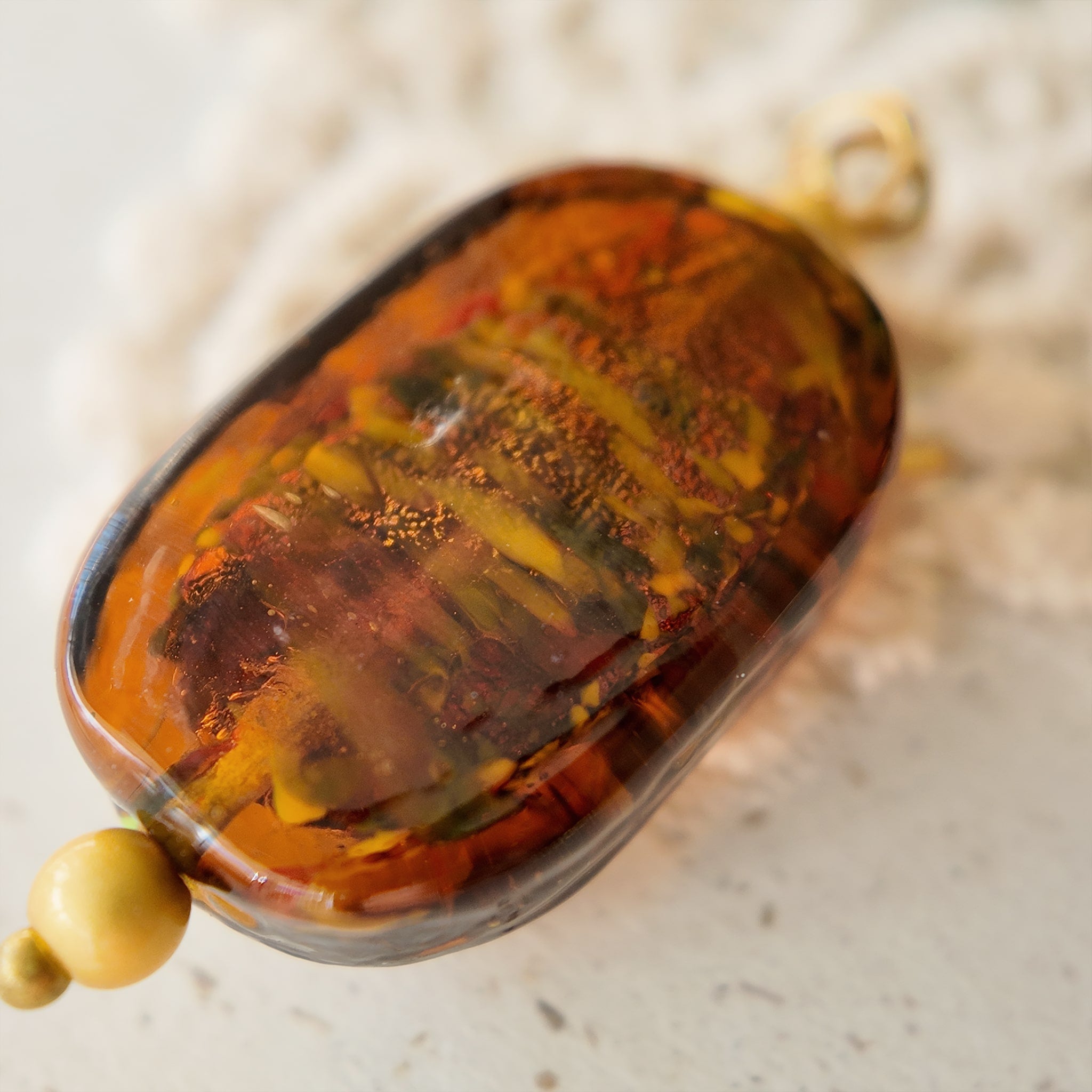 The reverse side of the Hemingway-inspired "Leaping Wanderer" charm, showcasing the smooth finish of the glass and the handcrafted assembly.