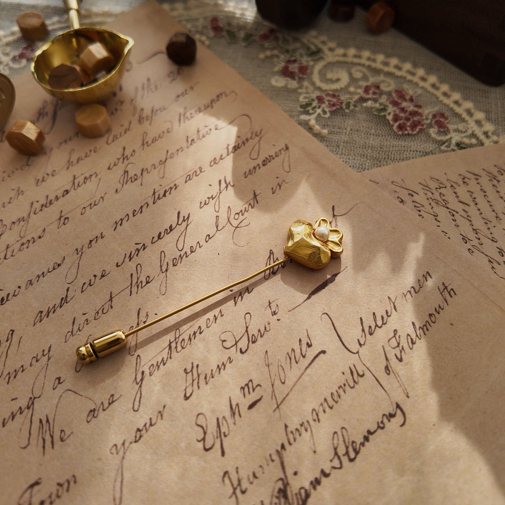 The "Secret Magician" heart brooch styled next to a fountain pen and a handwritten letter to emphasize its intellectual, Light Academia and poetic aesthetic.