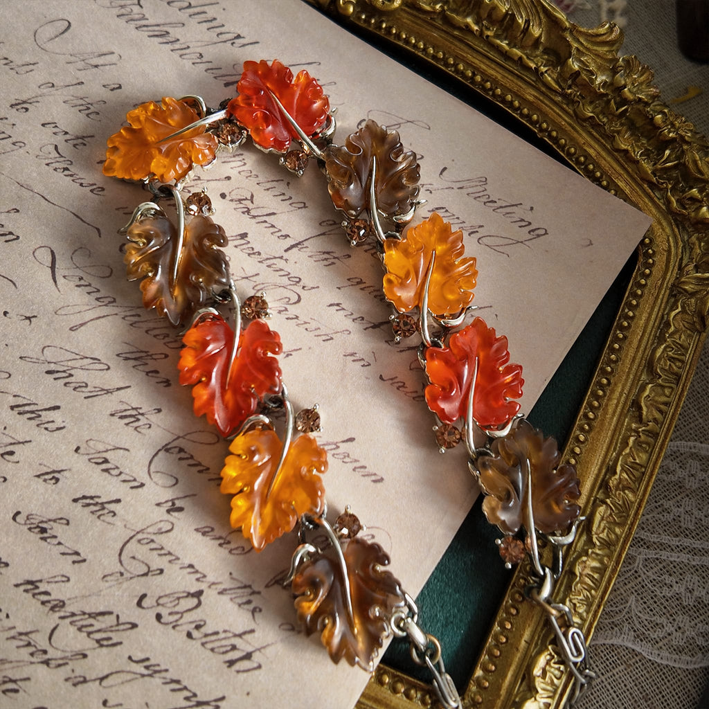 An angled view of the botanical necklace, highlighting the beautiful, semi-translucent quality of the hand-carved Lucite leaves that glow like candy.