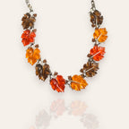 The "Sunshine Carrier," an iconic vintage Lisner statement necklace, featuring a cascade of carved Lucite leaves in vibrant orange, amber, and yellow hues.