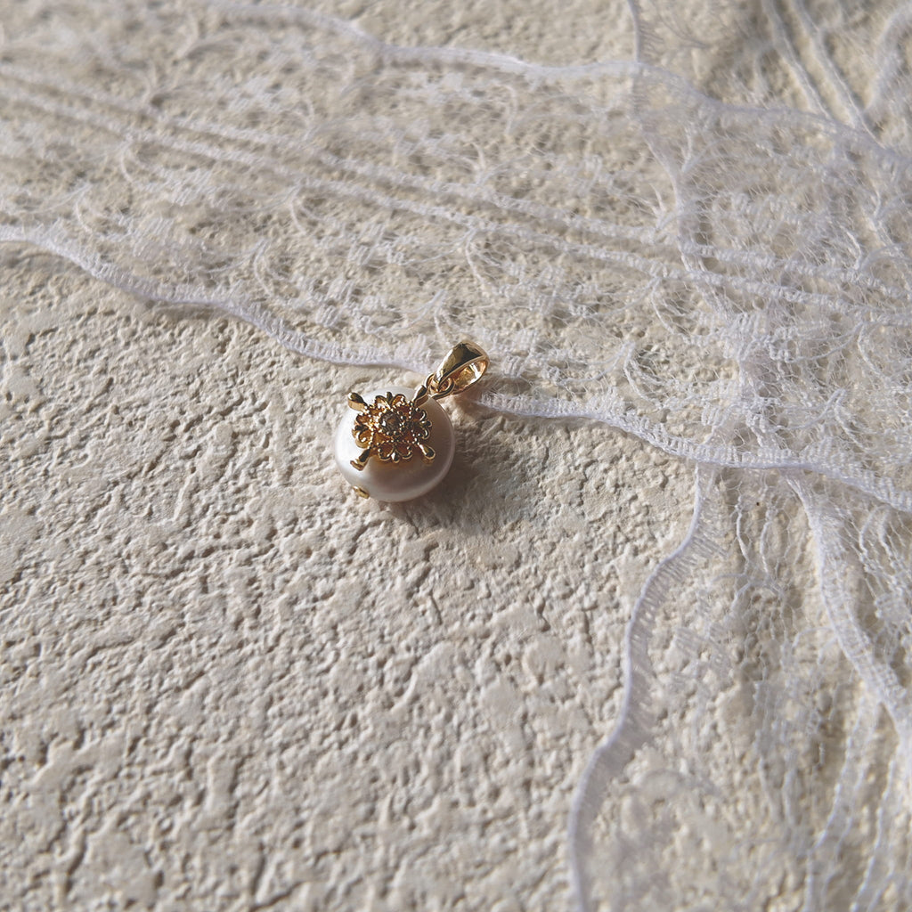 A macro shot detailing the soft, natural luster of the freshwater pearl and the tiny, star-like sparkle of the central cubic zirconia in the filigree.