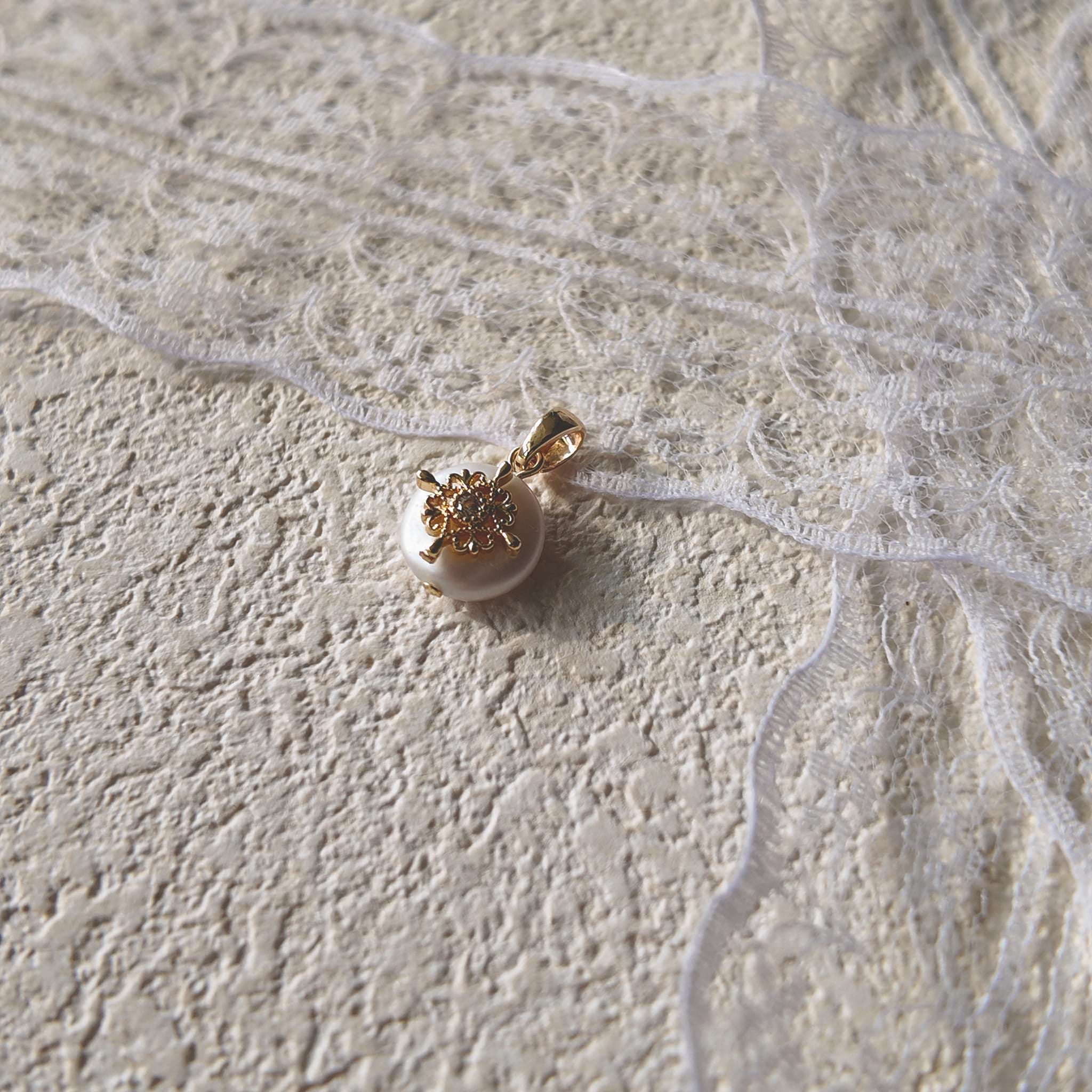 A macro shot detailing the soft, natural luster of the freshwater pearl and the tiny, star-like sparkle of the central cubic zirconia in the filigree.