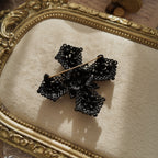 A close-up of the authentic "M.JENT" signature stamped on the reverse of the vintage 1980s Gothic cross brooch.