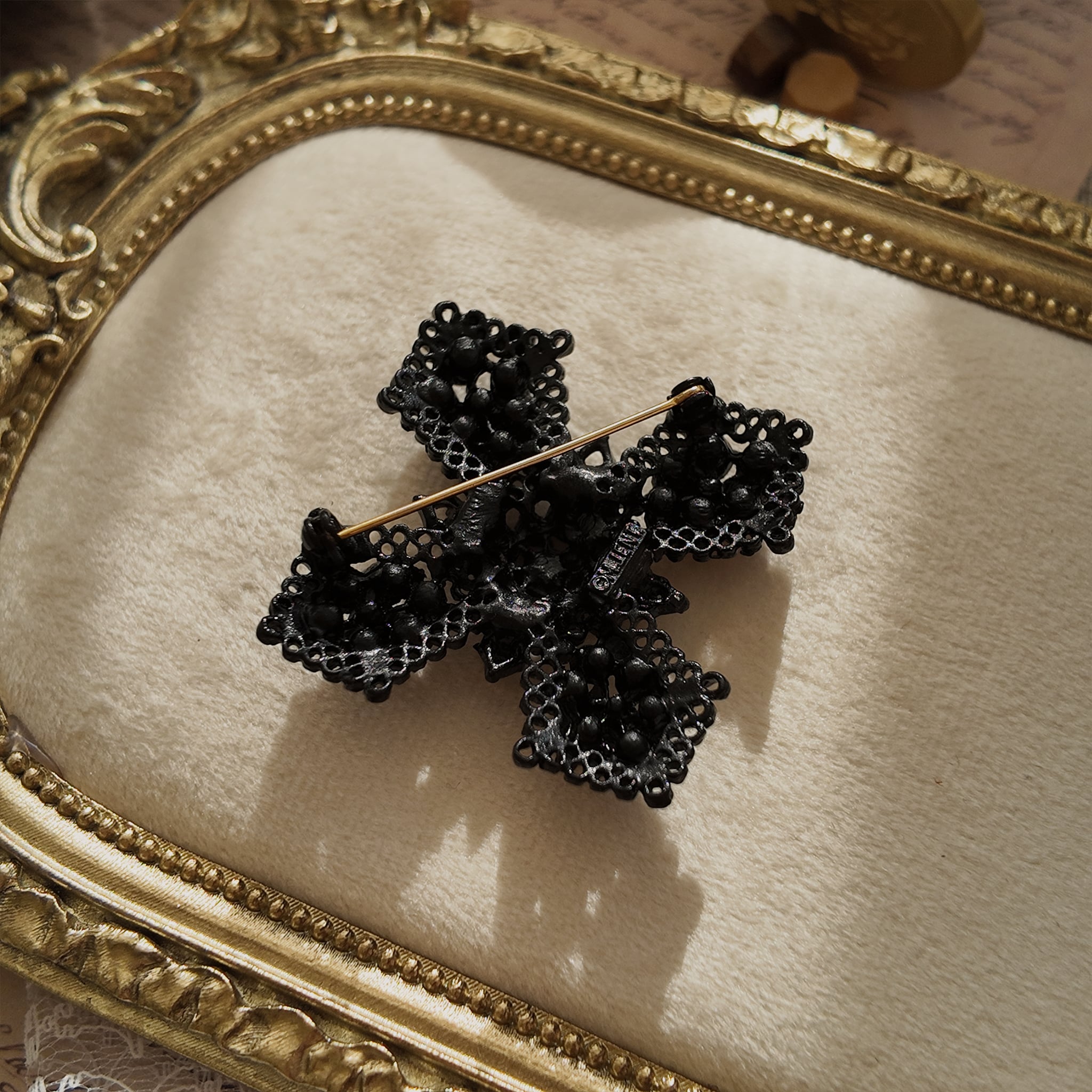 A close-up of the authentic "M.JENT" signature stamped on the reverse of the vintage 1980s Gothic cross brooch.