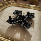 A close-up of the authentic "M.JENT" signature stamped on the reverse of the vintage 1980s Gothic cross brooch.