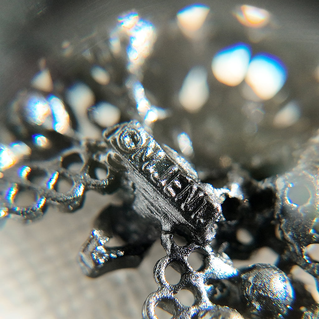 A close-up of the authentic "M.JENT" signature stamped on the reverse of the vintage 1980s Gothic cross brooch.