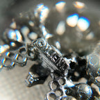 A close-up of the authentic "M.JENT" signature stamped on the reverse of the vintage 1980s Gothic cross brooch.