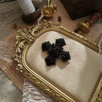 The "Vampire Matriarch," an all-black Gothic cross brooch by M.Jent, featuring intricate, web-like filigree and black rhinestone details.