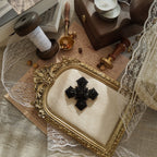 The "Vampire Matriarch," an all-black Gothic cross brooch by M.Jent, featuring intricate, web-like filigree and black rhinestone details.