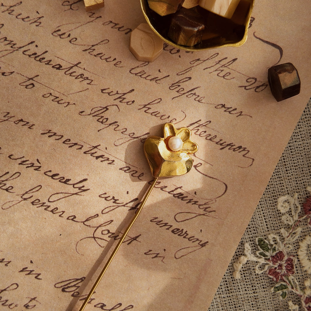 A macro shot detailing the perfect, smooth union of the lustrous white pearl and the warm, matte gold of this delicate piece of romantic jewelry.