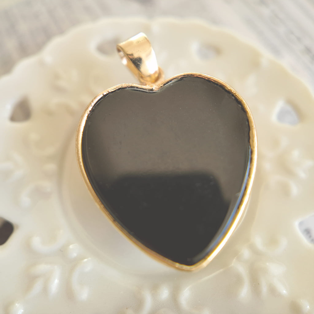Texture detail of the opaque jet black onyx heart, polished to a high shine and feeling cool to the touch.